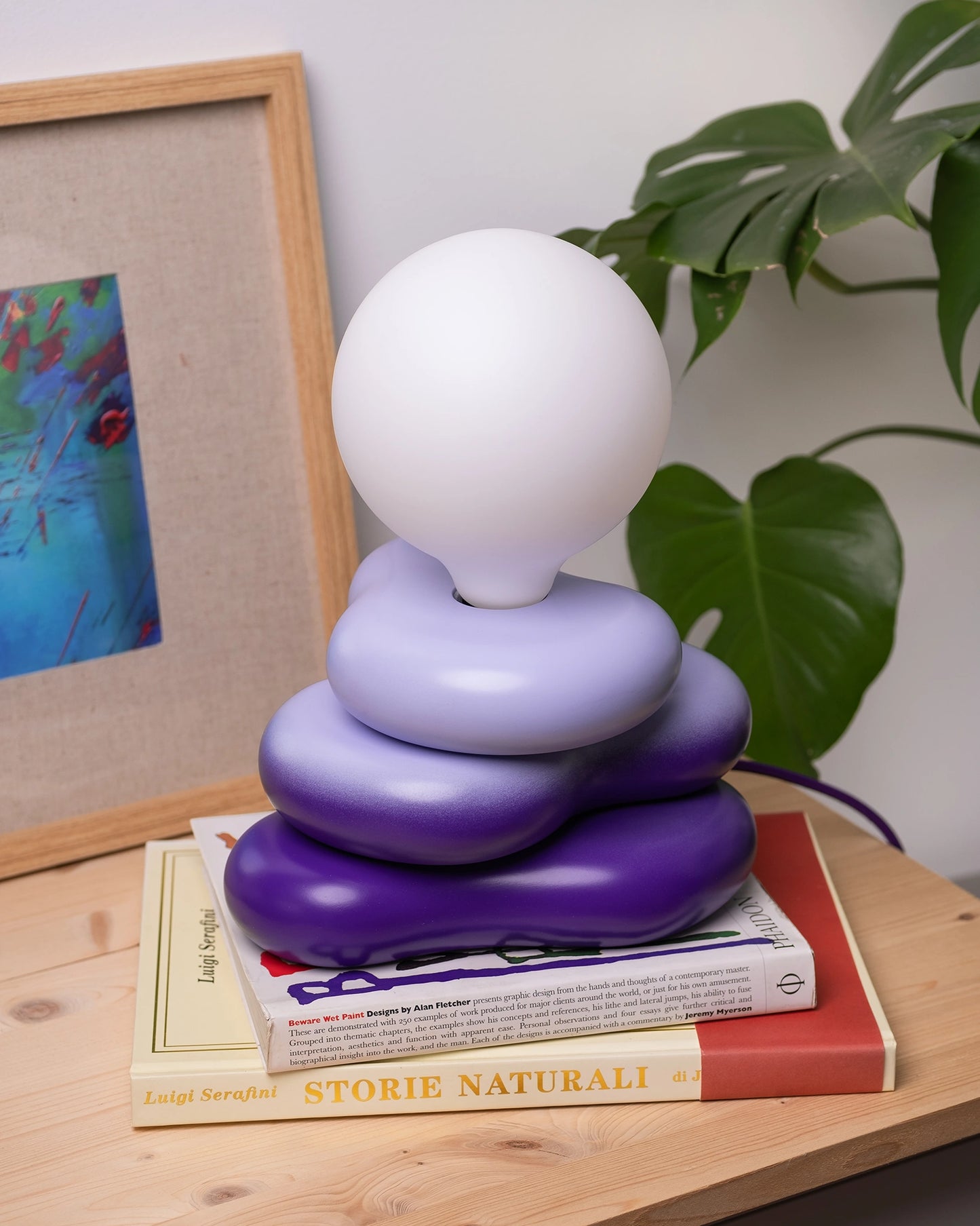 desk lamp in a home setting with round bulb and soft shaped wooden base, purple gradient 