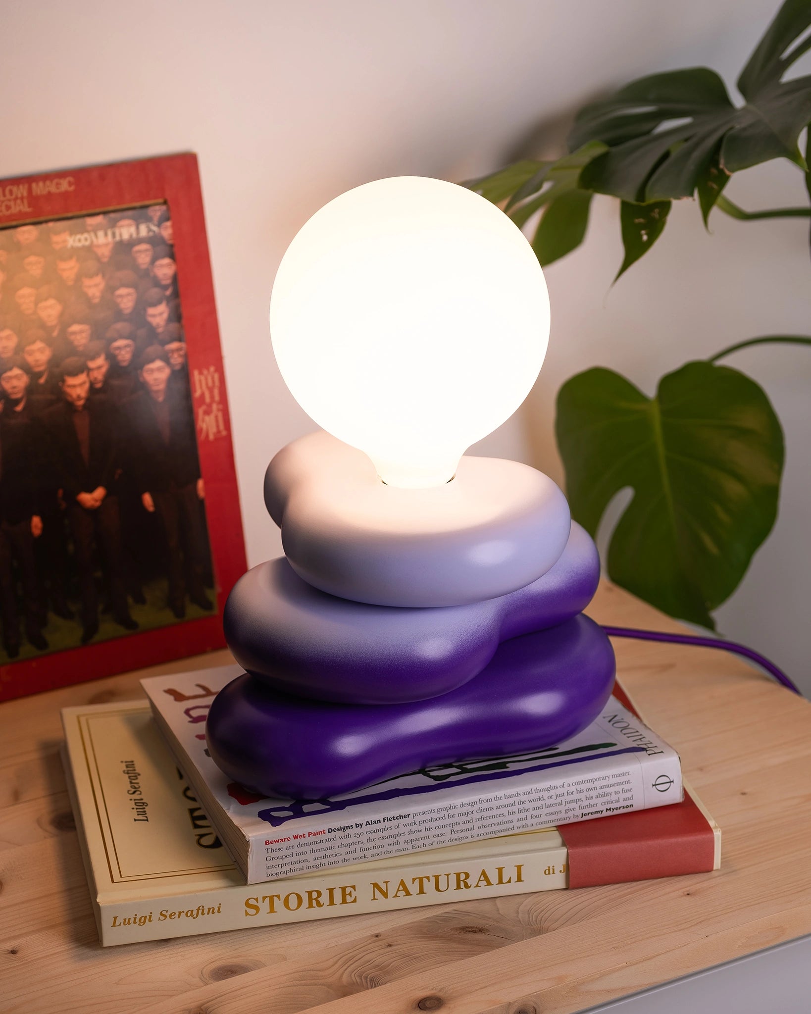 desk lamp in a home setting with round bulb and soft shaped wooden base, purple gradient 