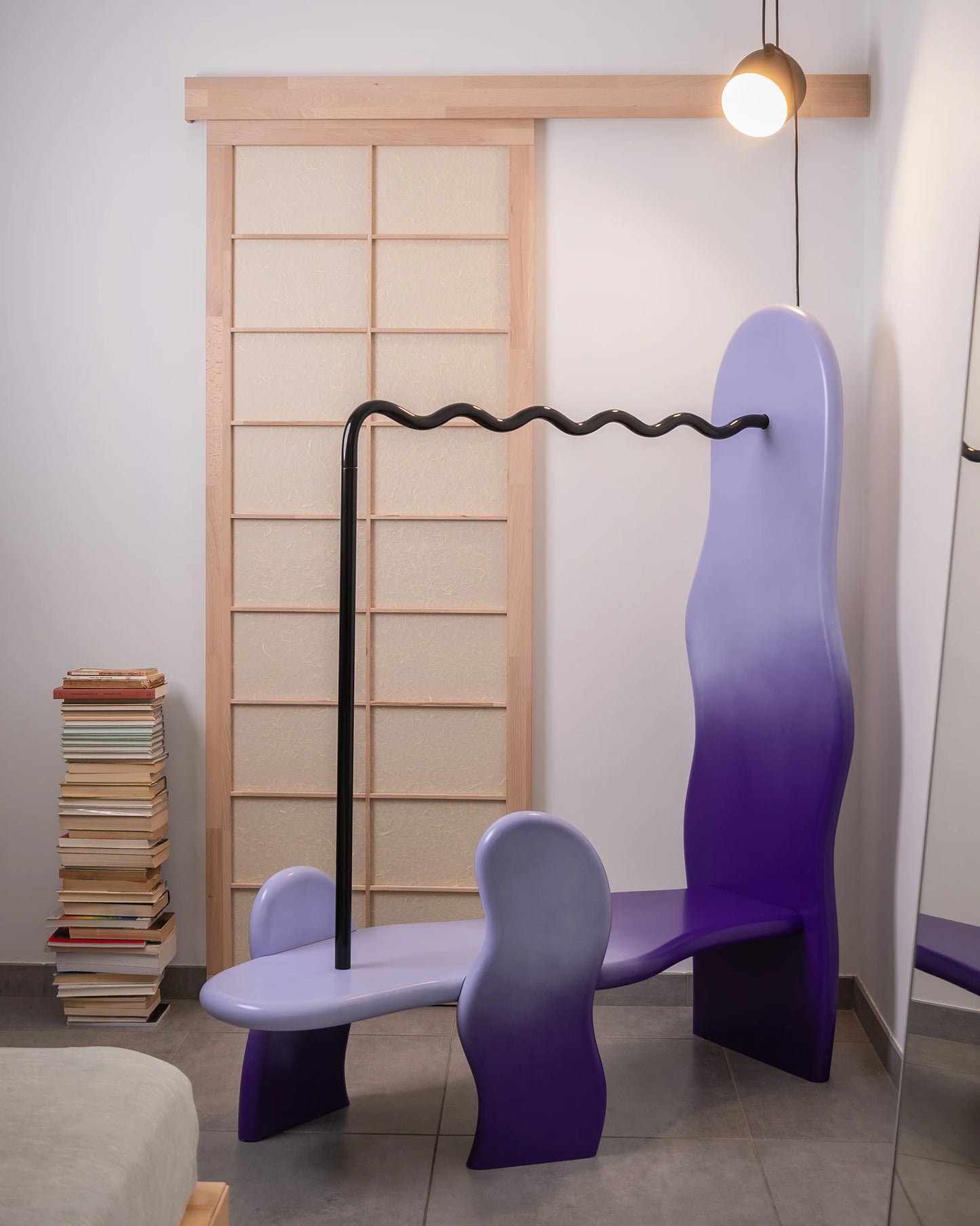 clothing rack in a home setting with soft shapes and a wavy metal hanging tube, purple gradient