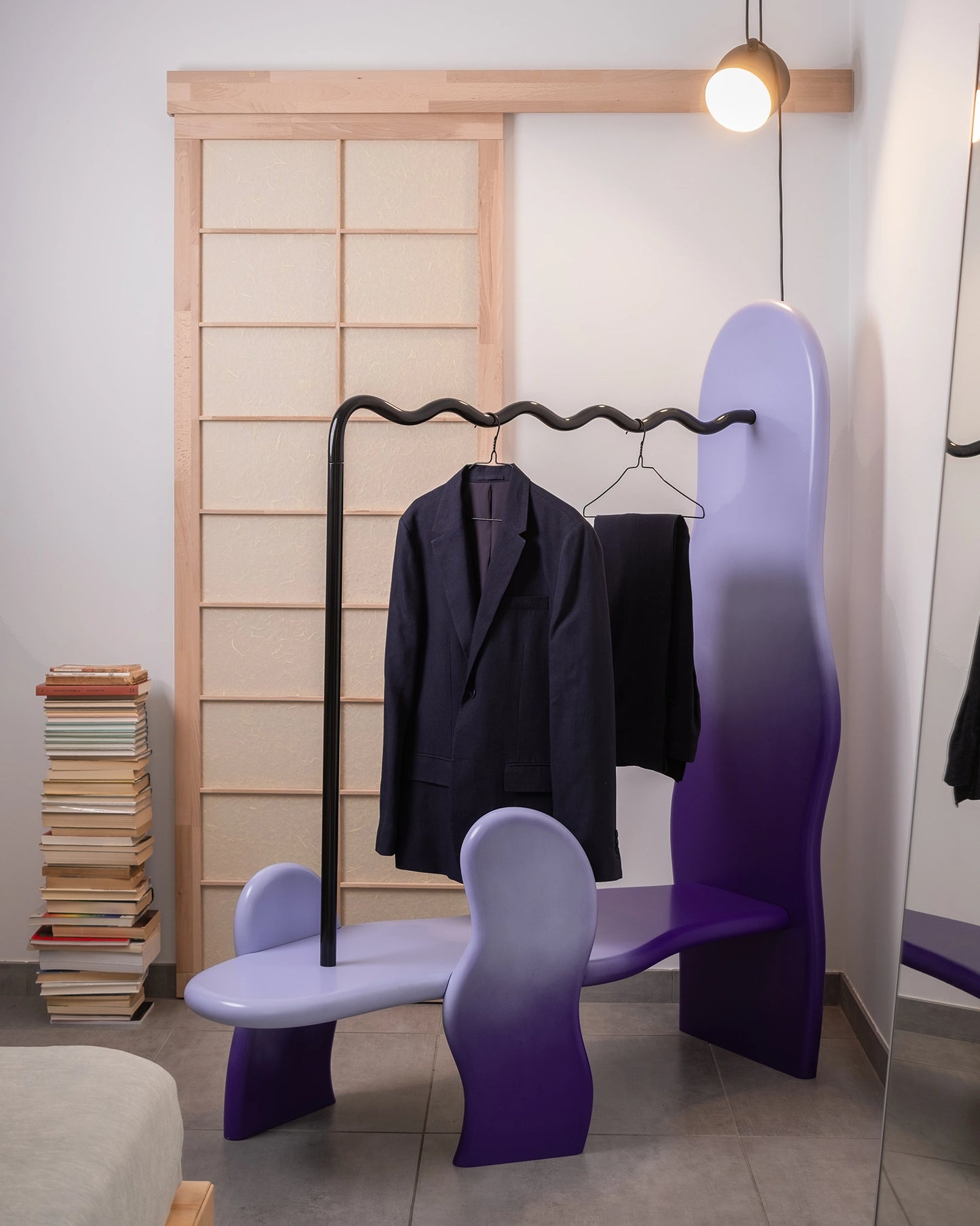 clothing rack in a home setting with soft shapes and a wavy metal hanging tube, purple gradient, clothes on it